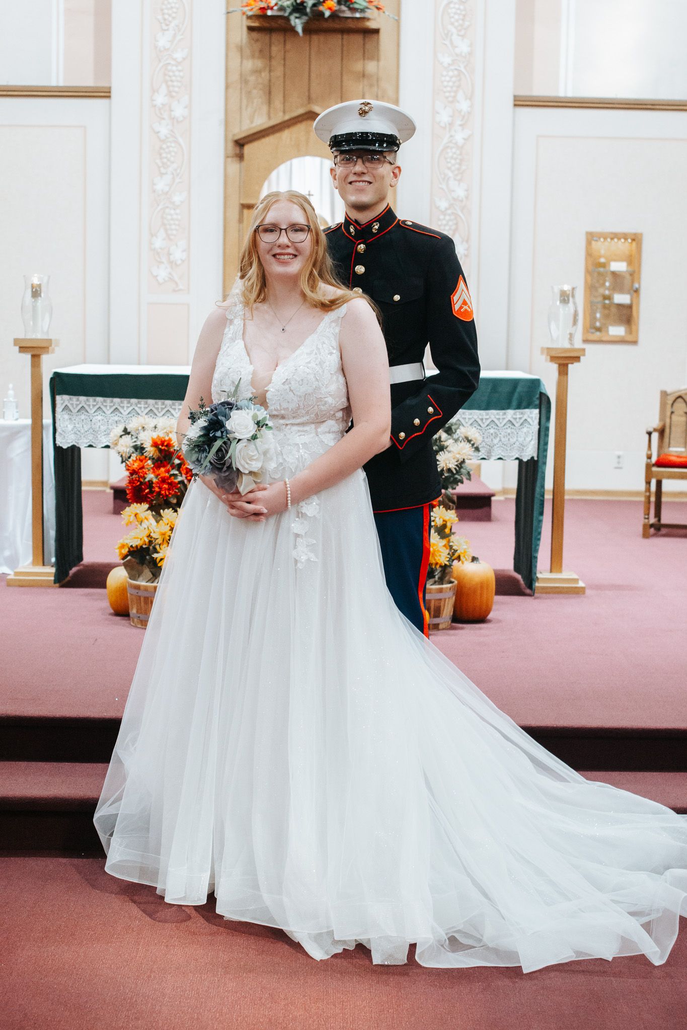Wedding couple poses for formal portraits in an elegant church interior with white decor.