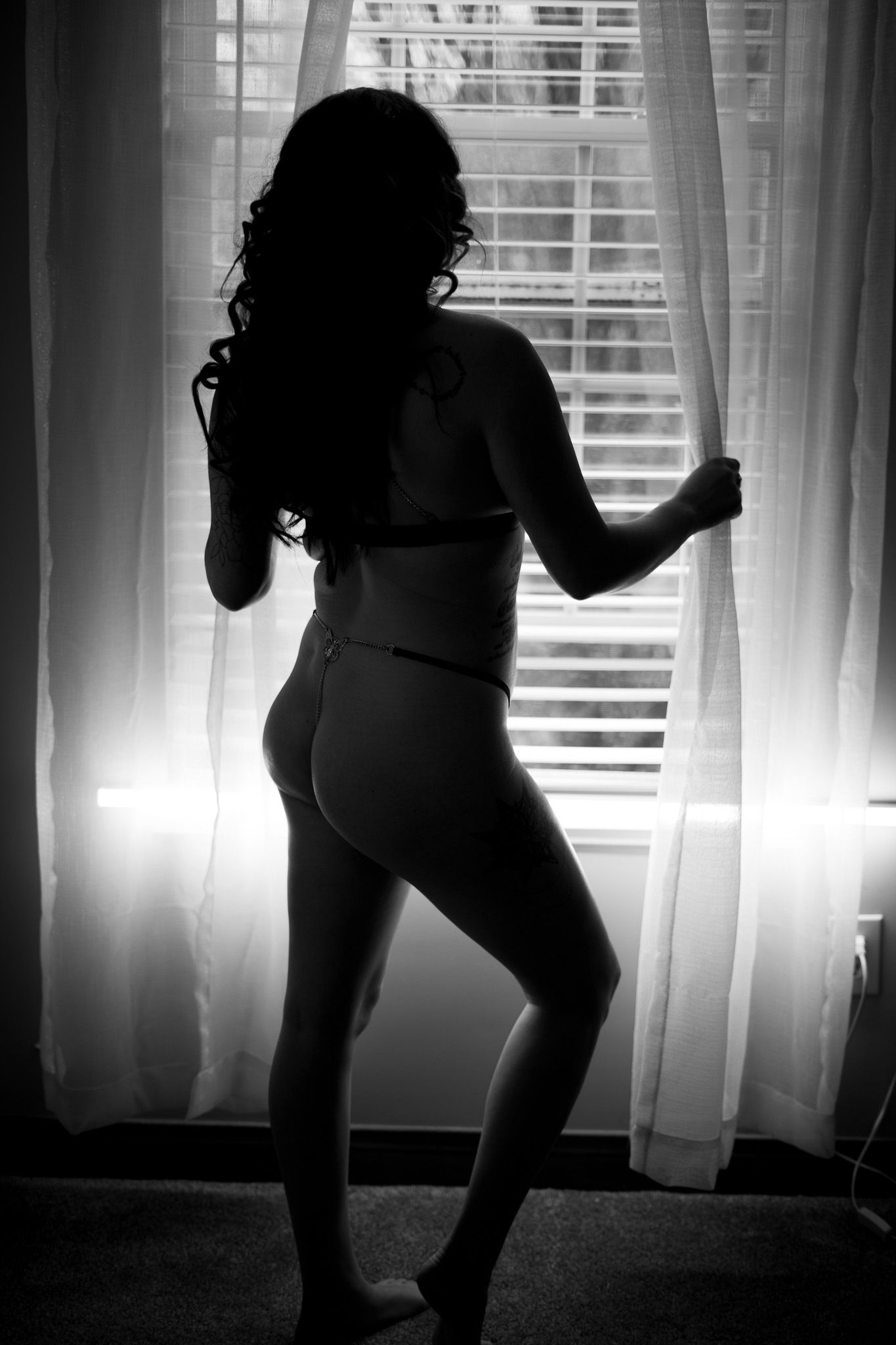 A series of silhouetted figures dancing in front of a window with bright backlighting creates a dramatic shadow effect.