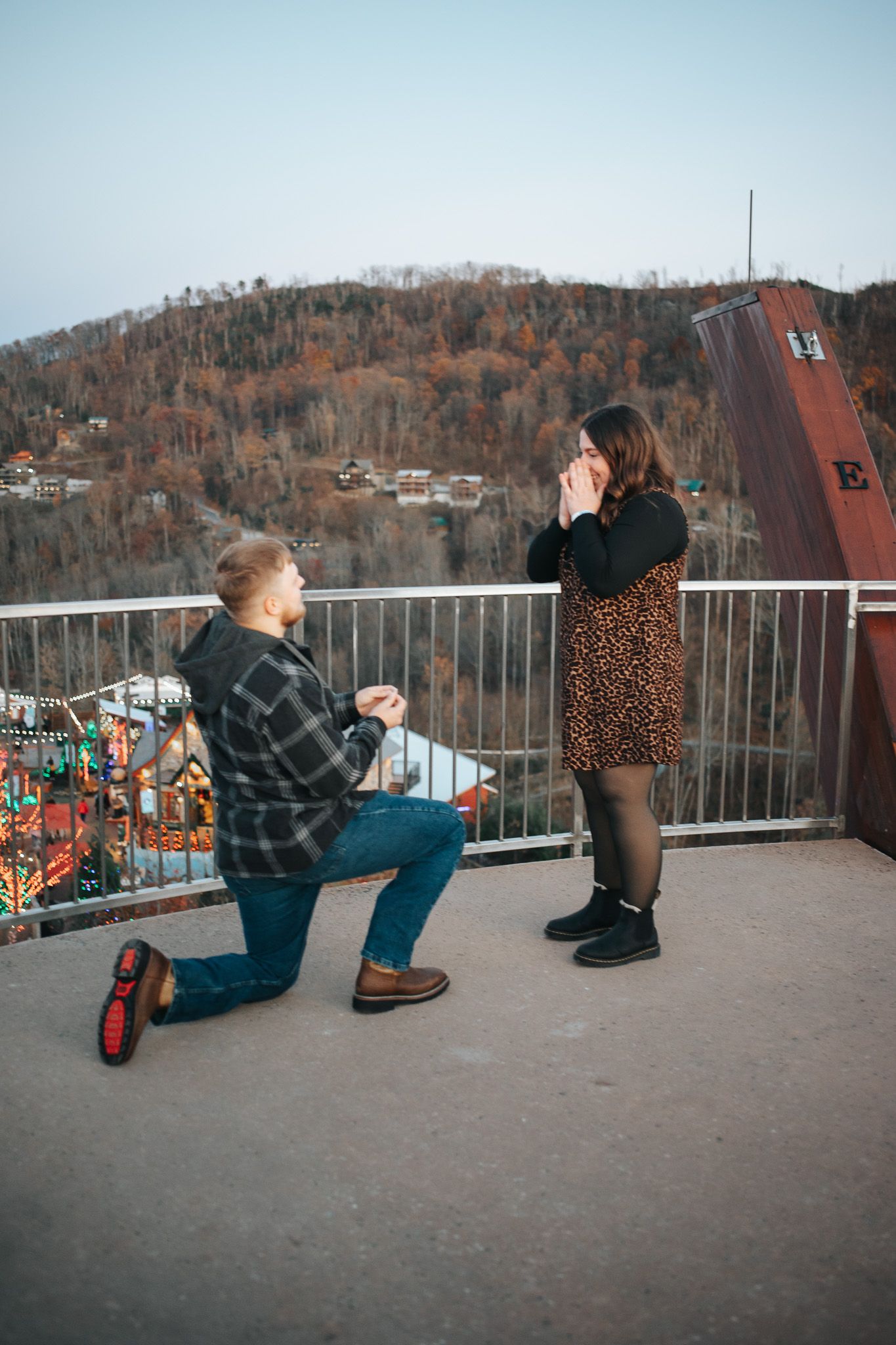 Proposal moment captured on an observation deck overlooking autumn mountain scenery.
