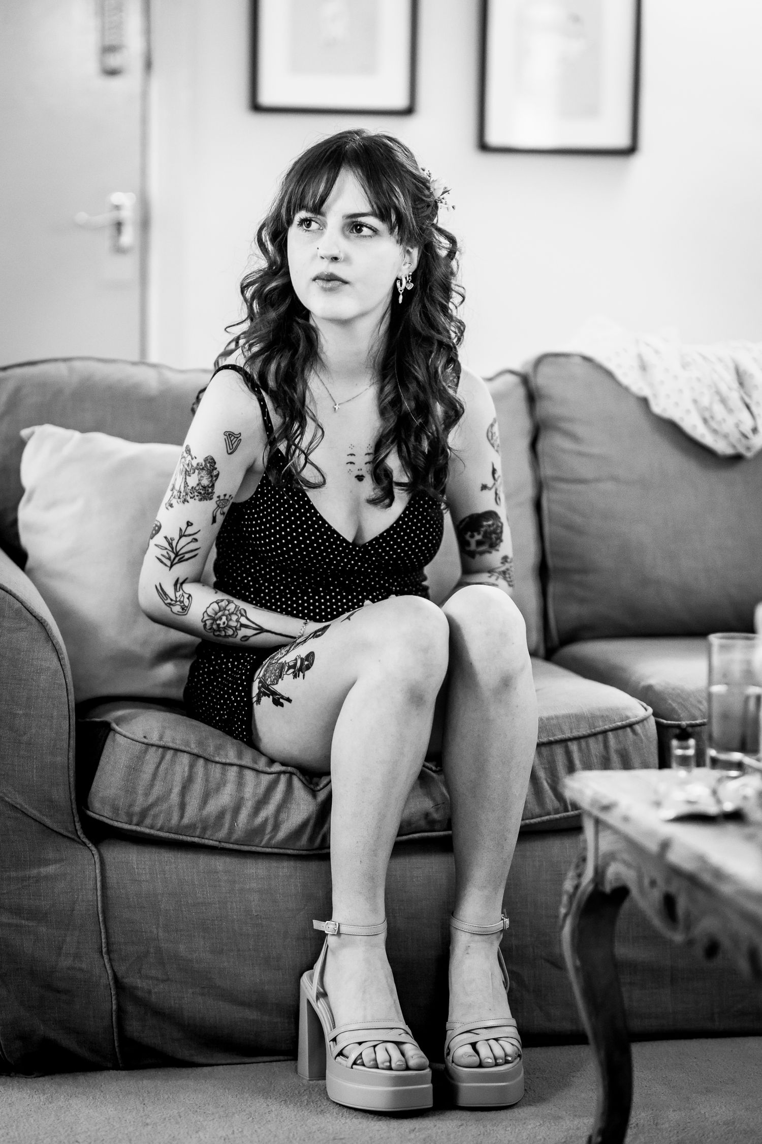Black and white portrait of someone in polka dot dress sitting on grey couch.
