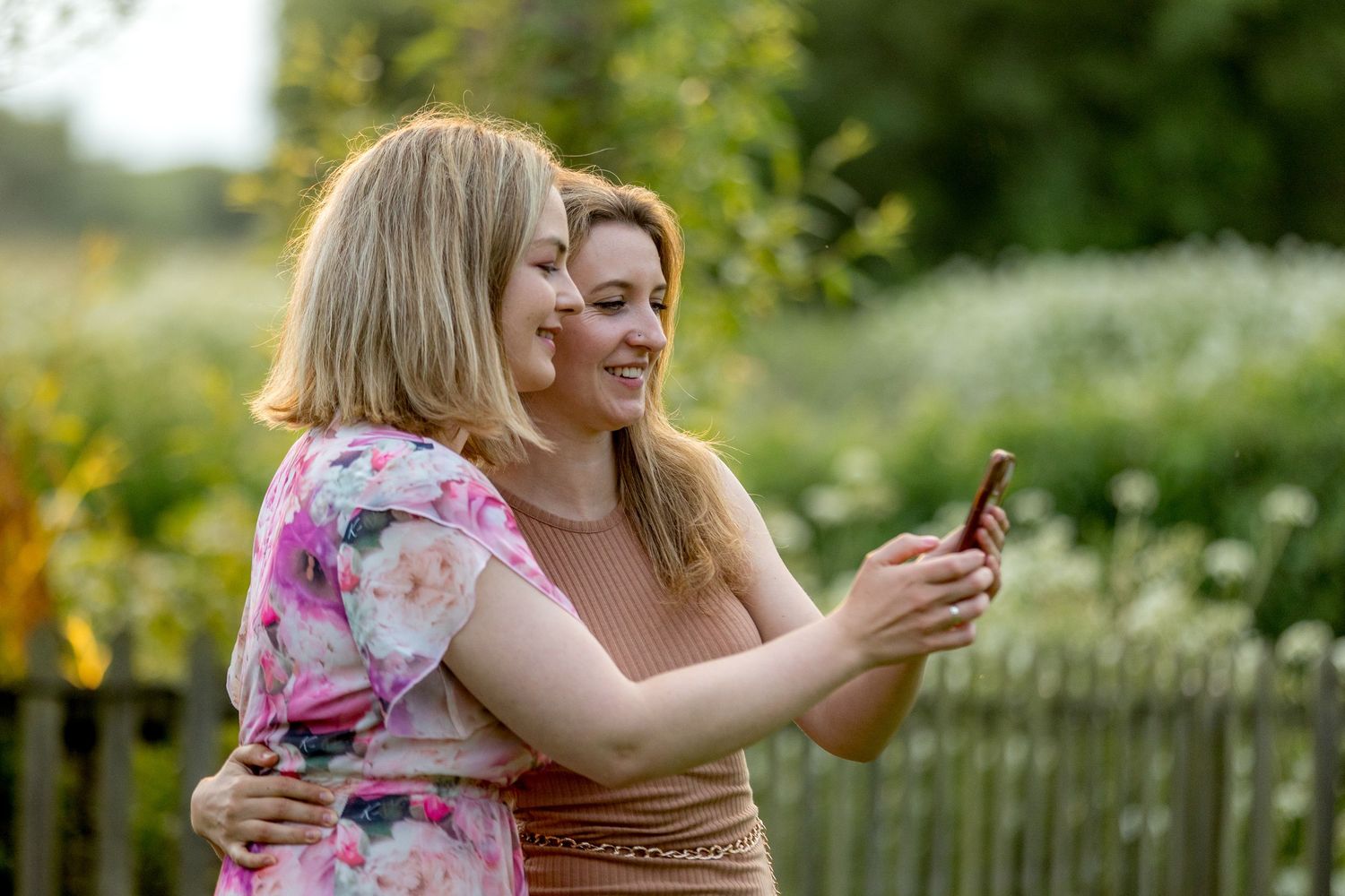 Wedding guests enjoying a casual outdoor gathering in a garden setting at sunset.