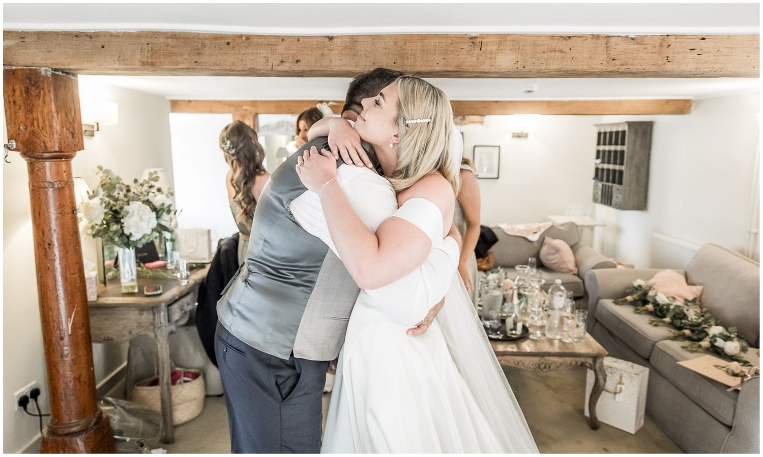 Wedding party gathering in a rustic venue with exposed wooden beams.