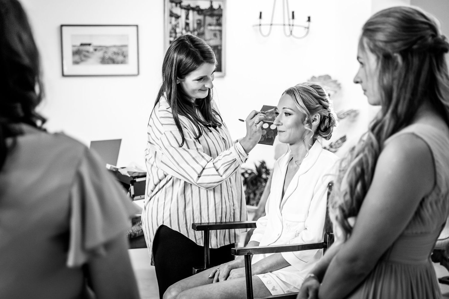 Wedding preparation scene with people getting ready in a well-lit room with framed artwork.