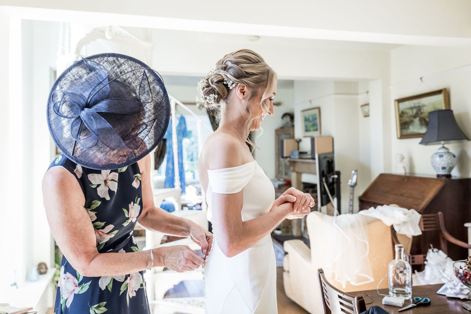 Wedding preparation scene in bright room with floral decorations and formal attire.