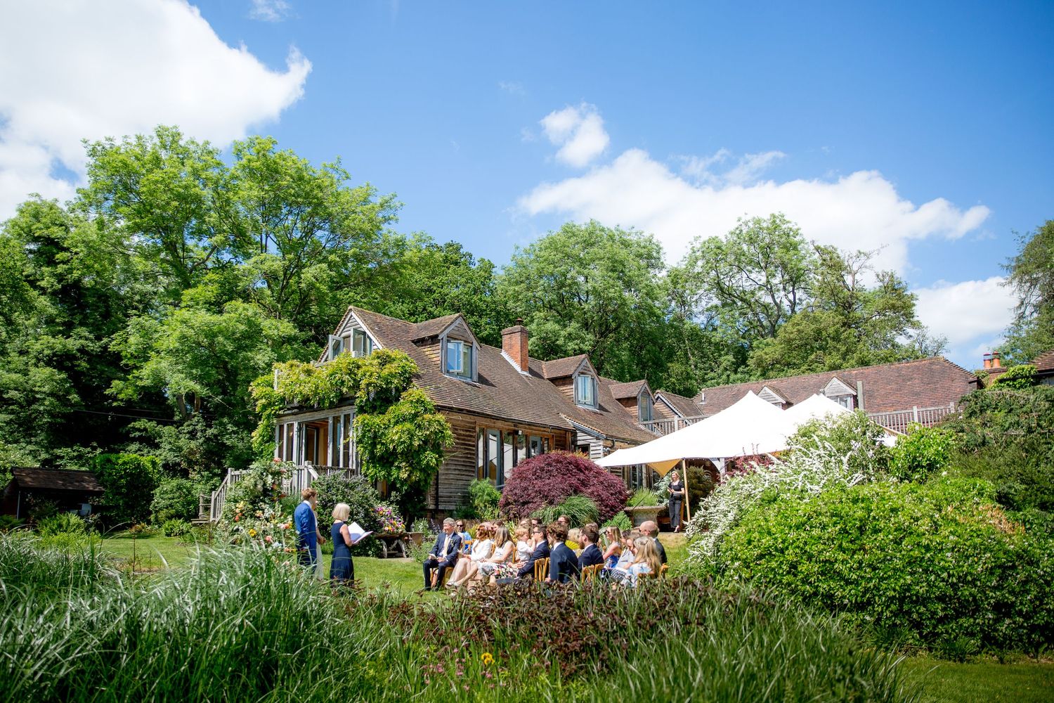 Panoramic view of a residential property with lush green landscaping and multiple buildings under a bright blue sky.