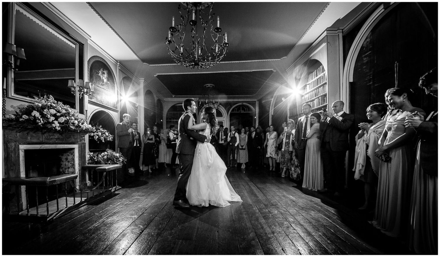 Dramatic black and white shot of ballroom reception with chandeliers.