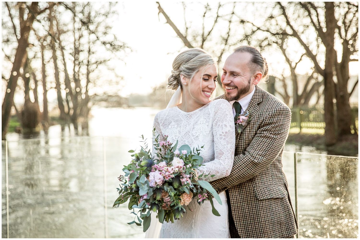 Intimate wedding photos taken by a lake during golden hour with bare winter trees.