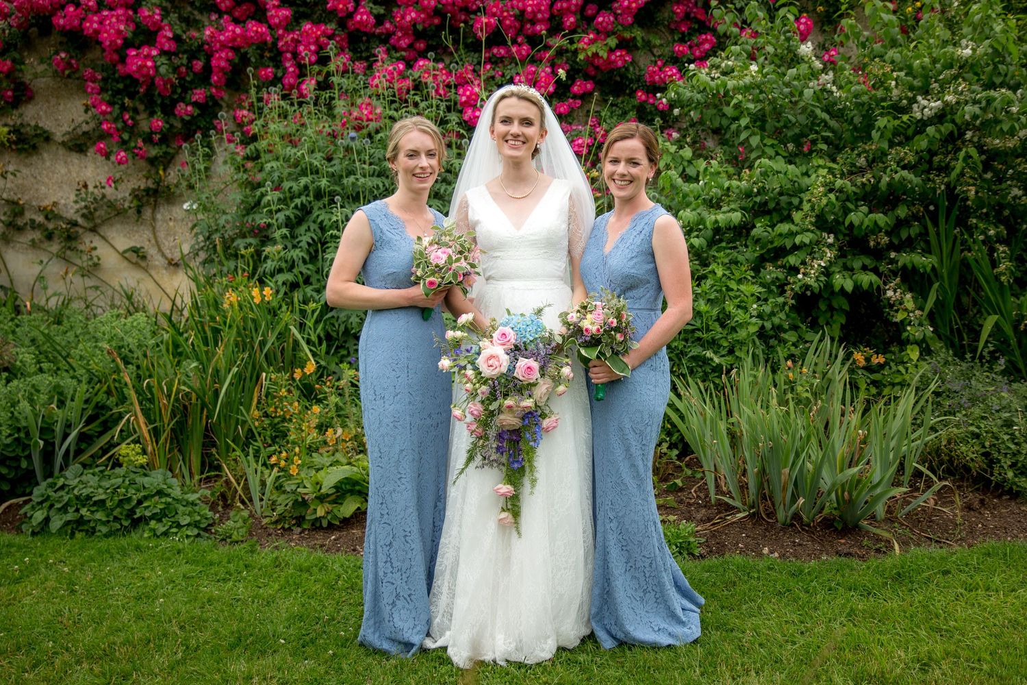 Bride and bridesmaids posed for a formal group photograph in the walled garden at Houghton Lodge