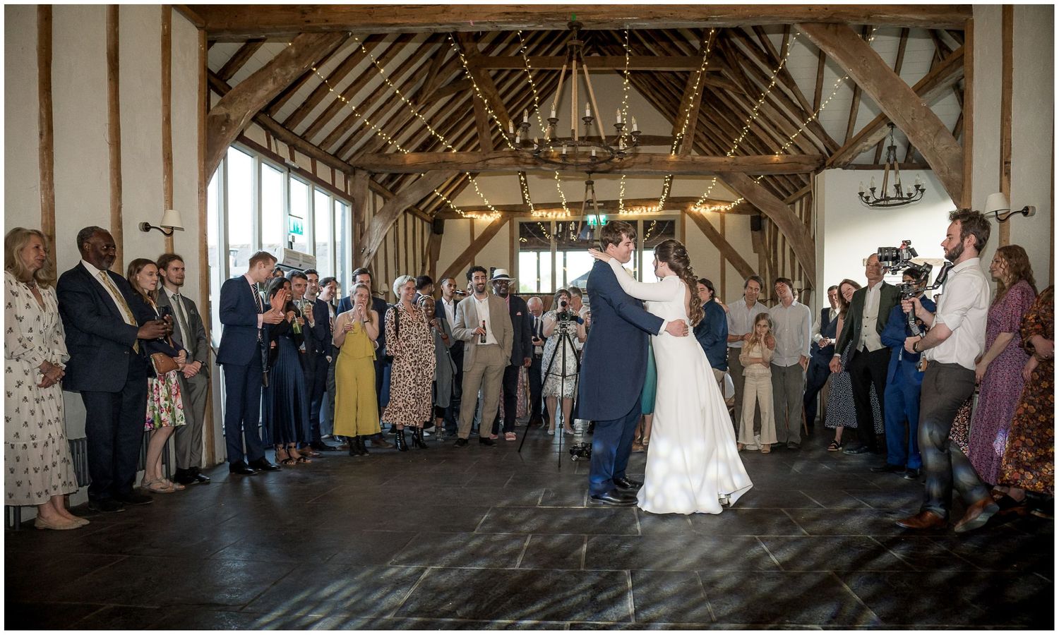 Wedding ceremony in a rustic barn venue with exposed wooden beams.