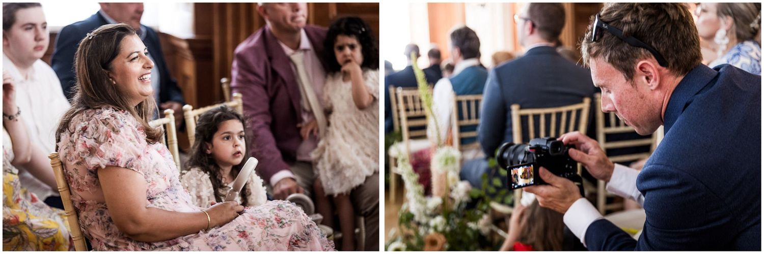 Wedding guests including a woman and young girl seated watching a ceremony, while a photographer captures moments on camera.