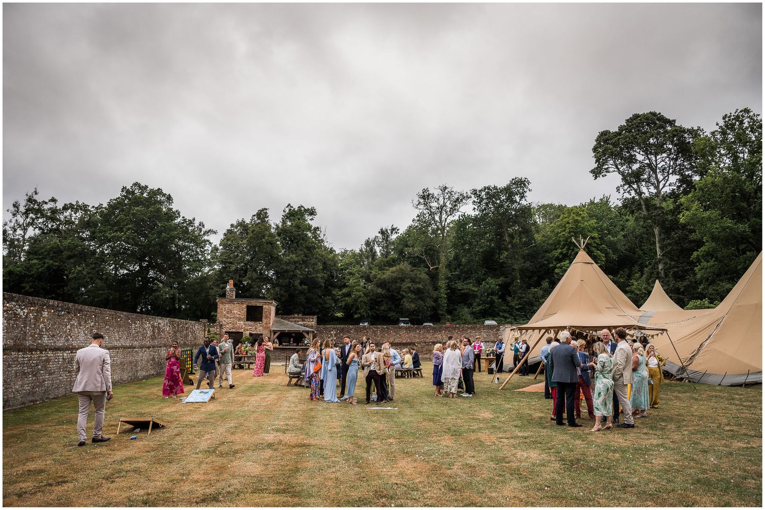 Marquee wedding reception with drinks outside the stretch tent in the walled garden at Holywell Estate near Winchester