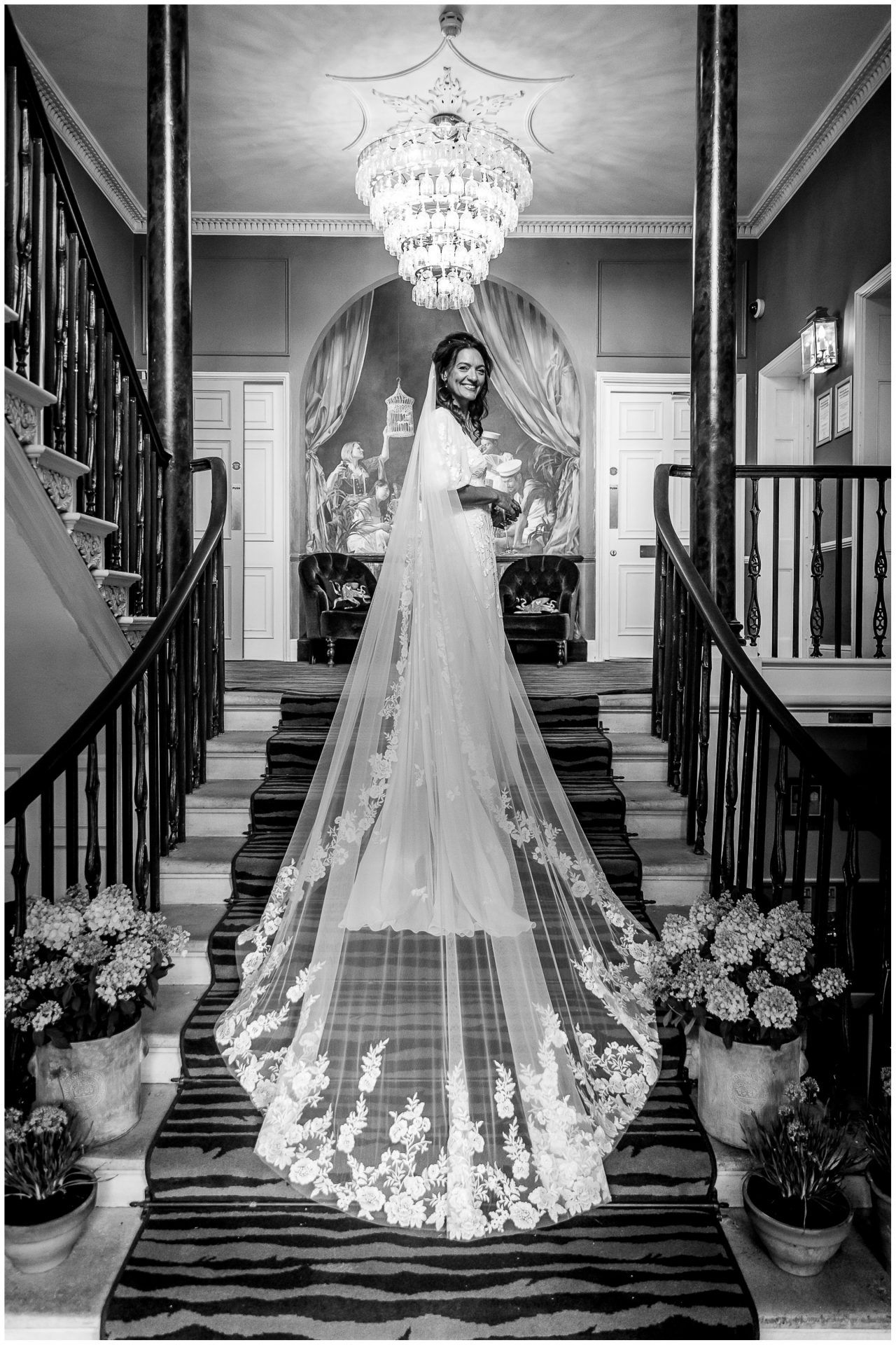 Dramatic black and white photos of a wedding dress with lace details on grand staircase.