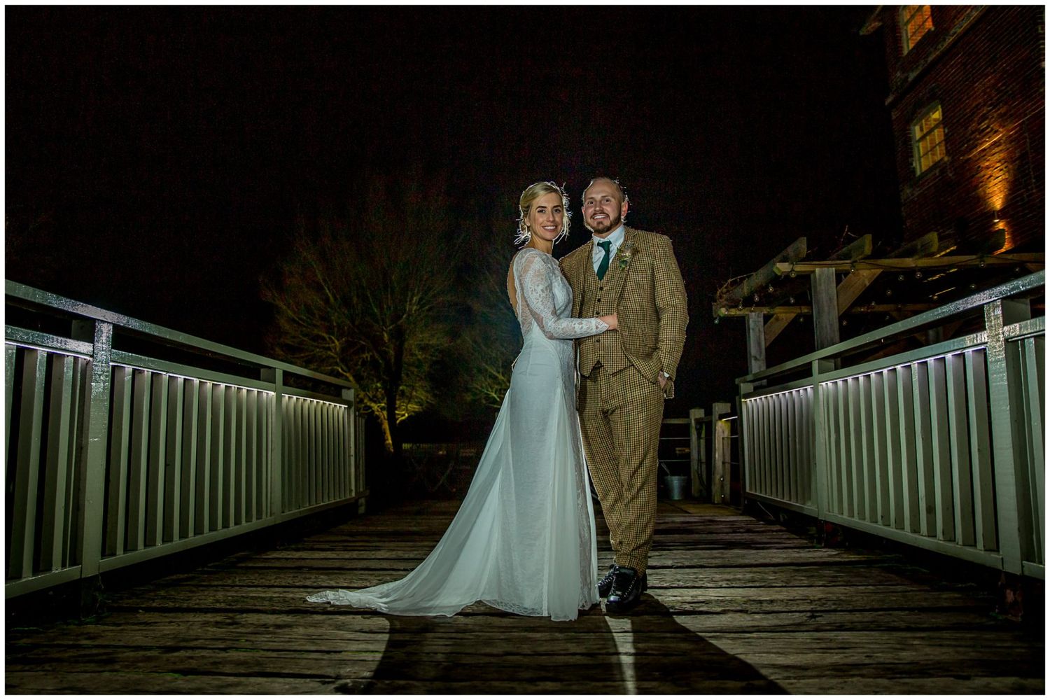 Romantic nighttime wedding photos on illuminated bridge walkway.