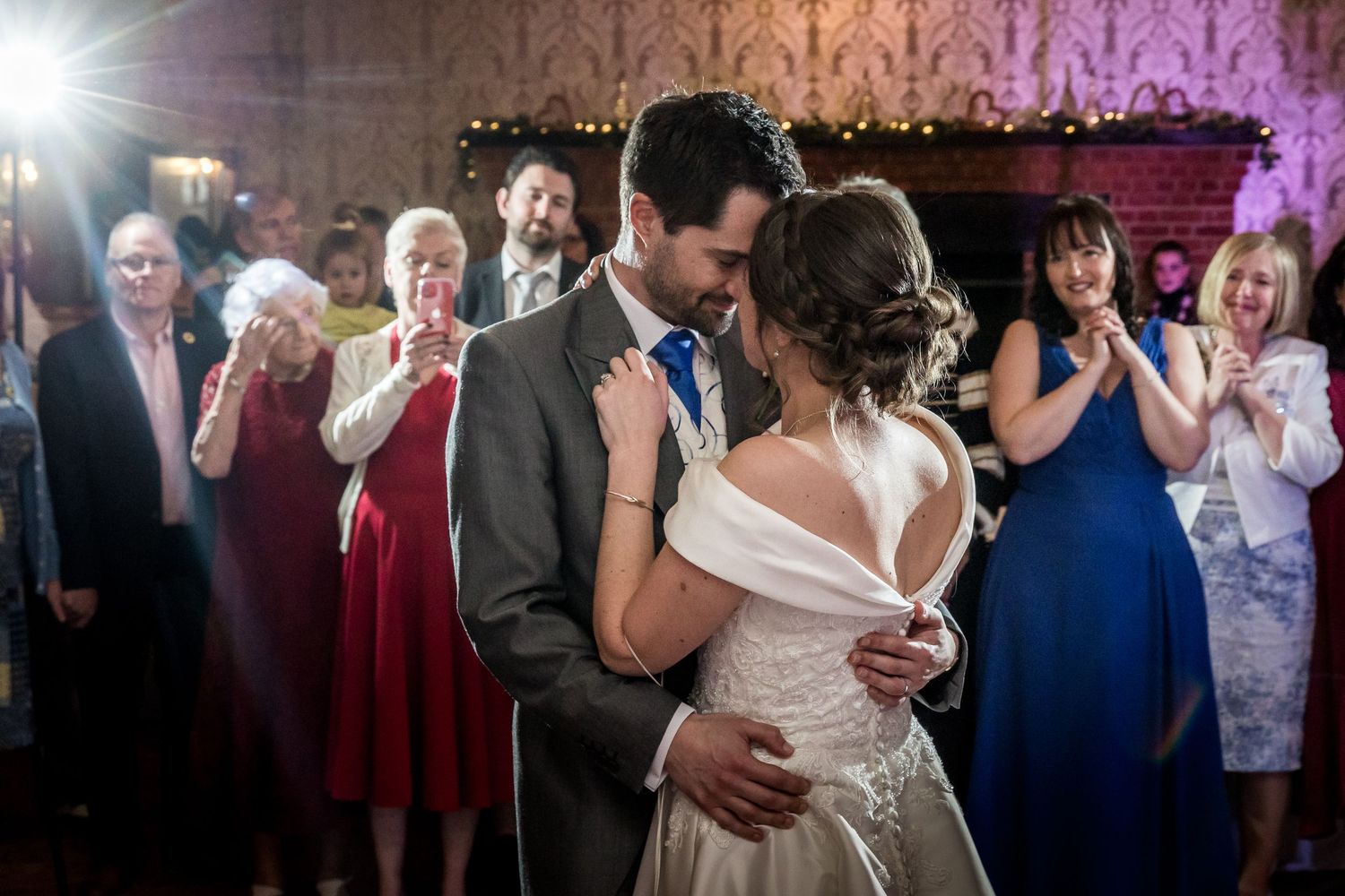 Couples dancing together at a wedding reception with purple lighting and guests watching in the background.