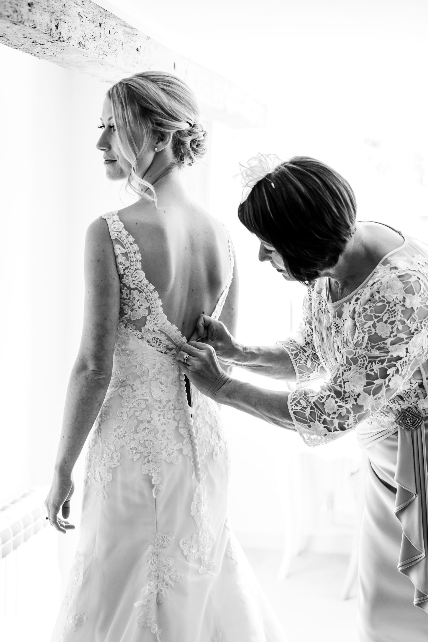 A series of ethereal black and white photos showing the delicate details of a wedding dress with lace and floral appliques.