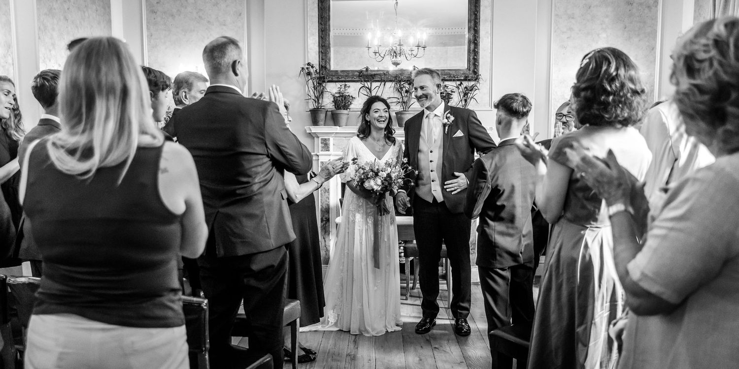 Wedding guests watching ceremony proceedings in an elegant indoor venue.