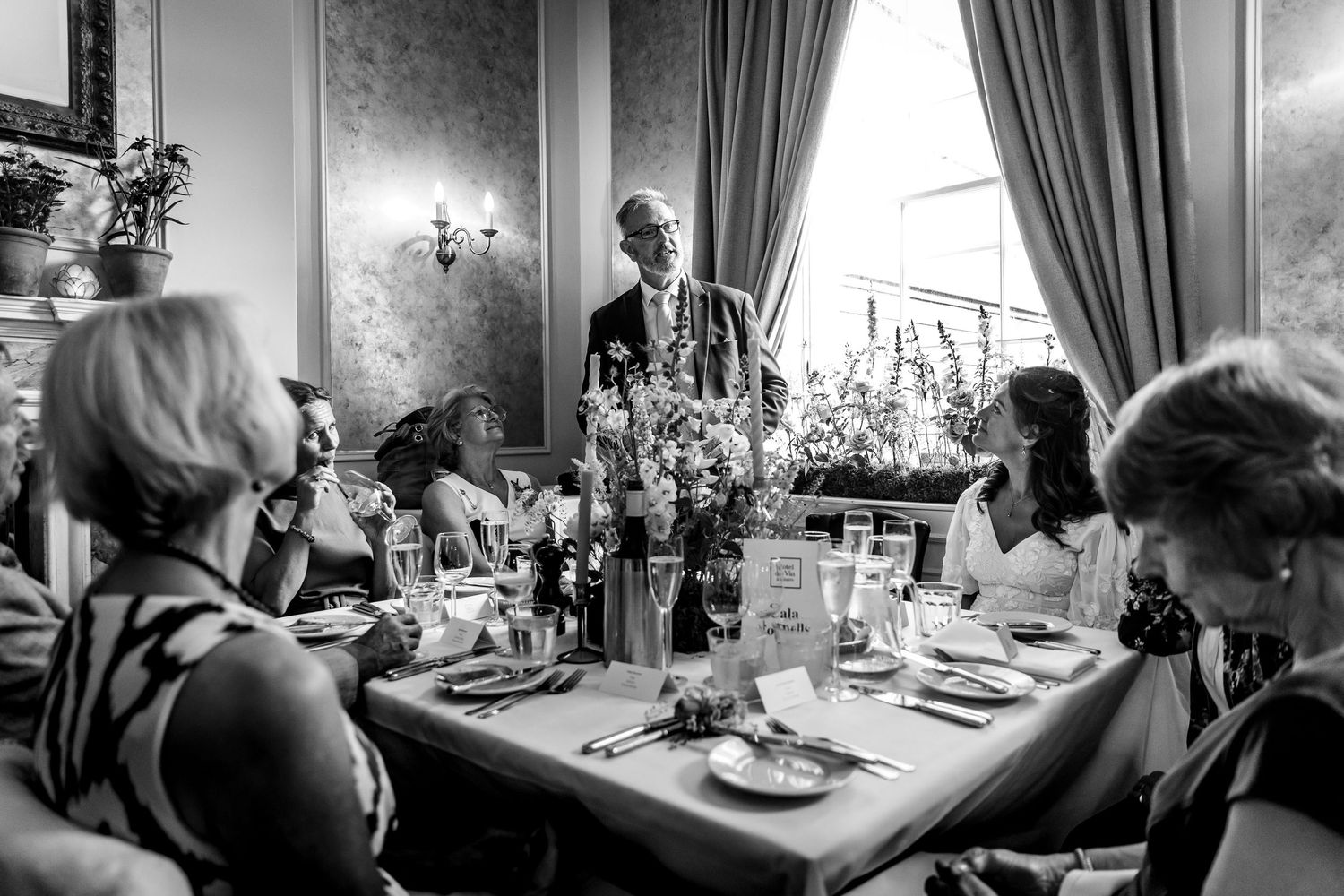 Elegant dining room setup with guests enjoying a wedding reception meal.