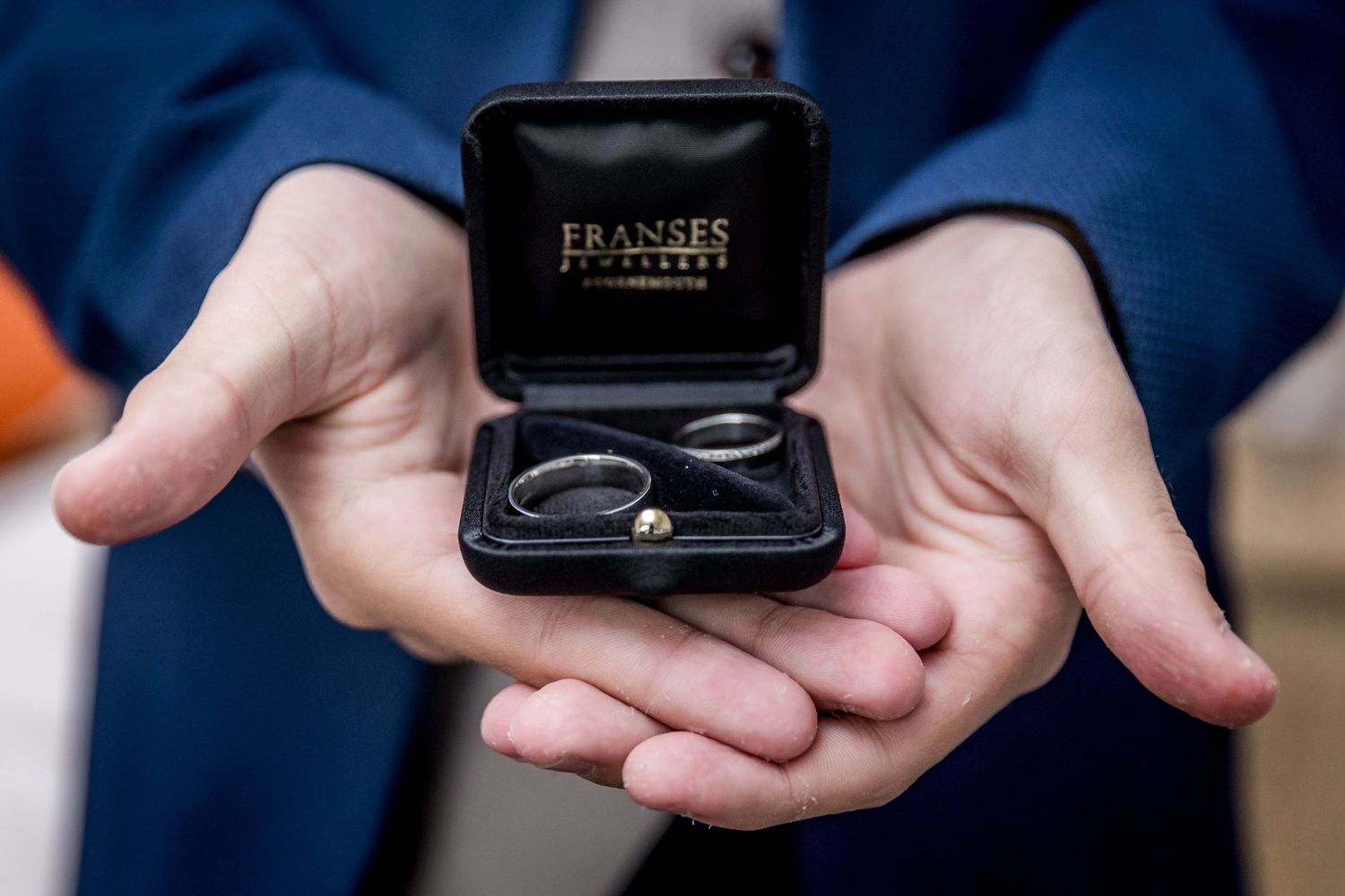 Close-up shots of hands holding a black ring box.