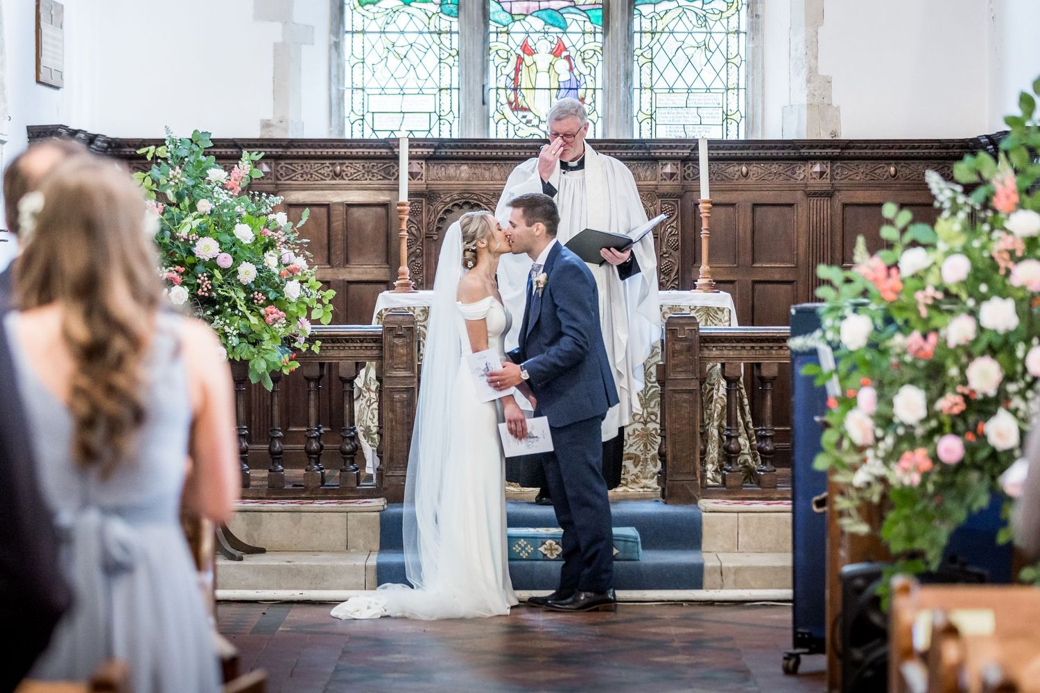 Wedding ceremony in progress at historic stone church with stained glass windows.