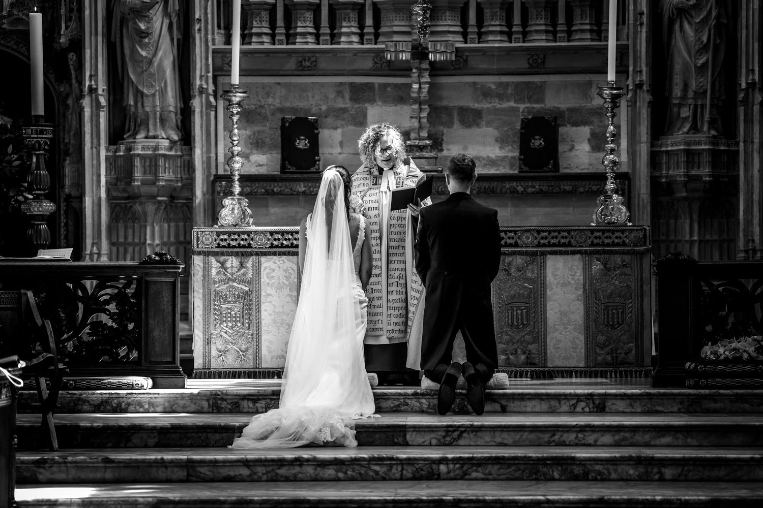 Black and white panoramic view of wedding ceremony in historic church interior.