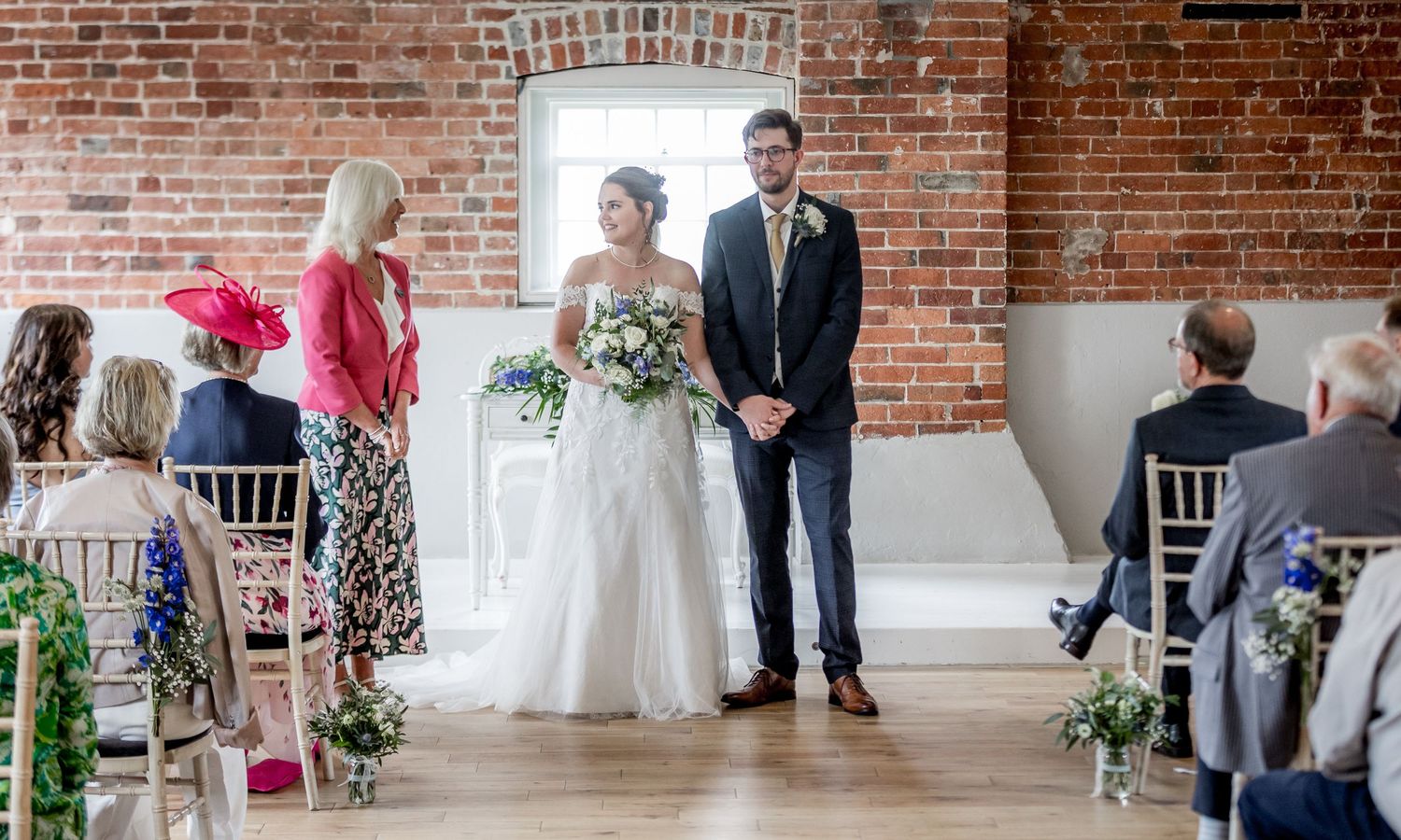 Wedding celebration in rustic venue with exposed brick and elegant white decor.
