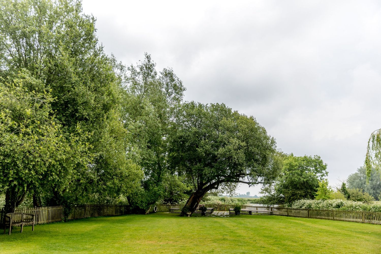 Scenic landscape view of a lush green garden with trees and cloudy sky.