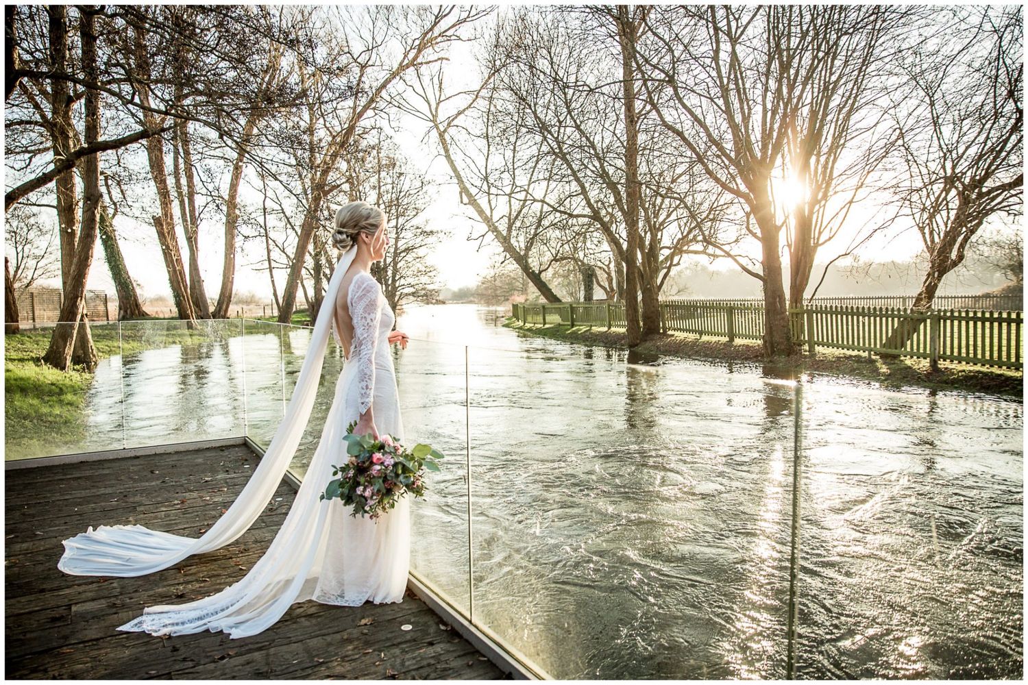 A bride stands on the decking looking over the river at Sopley Mill wedding venue in the New Forest, Hampshire
