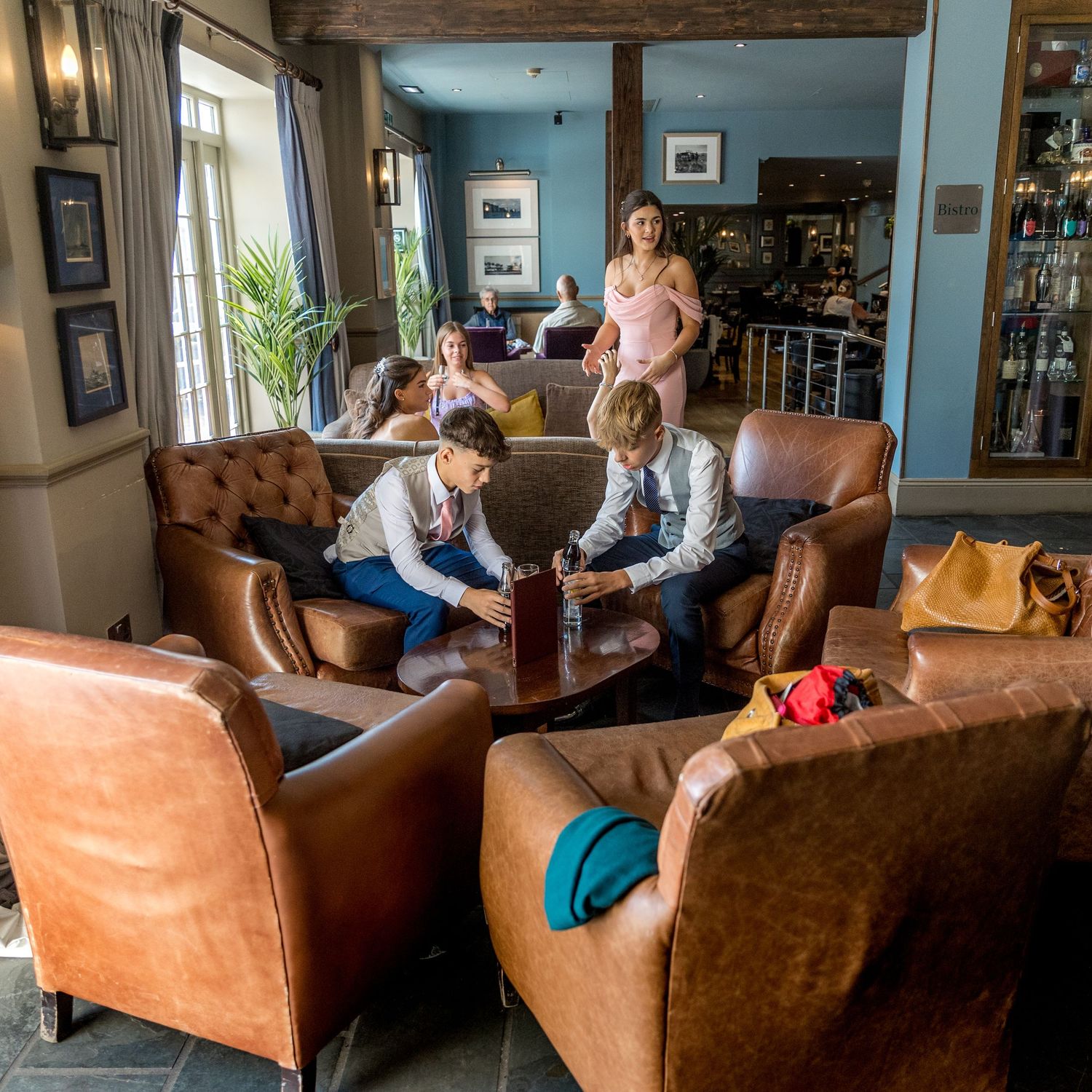 Cozy living room interior with leather sofas and blue walls during a gathering.