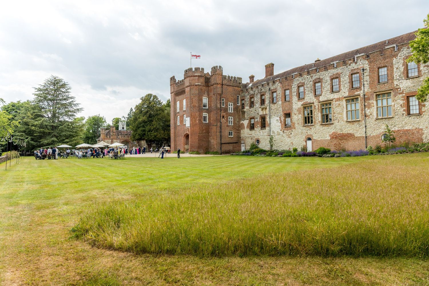 Medieval castle ruins with tower surrounded by green lawn and event tents.