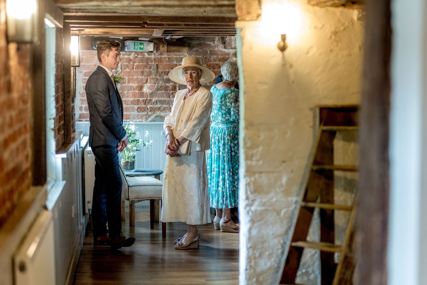 People gather in elegant hallway with brick walls and warm lighting.