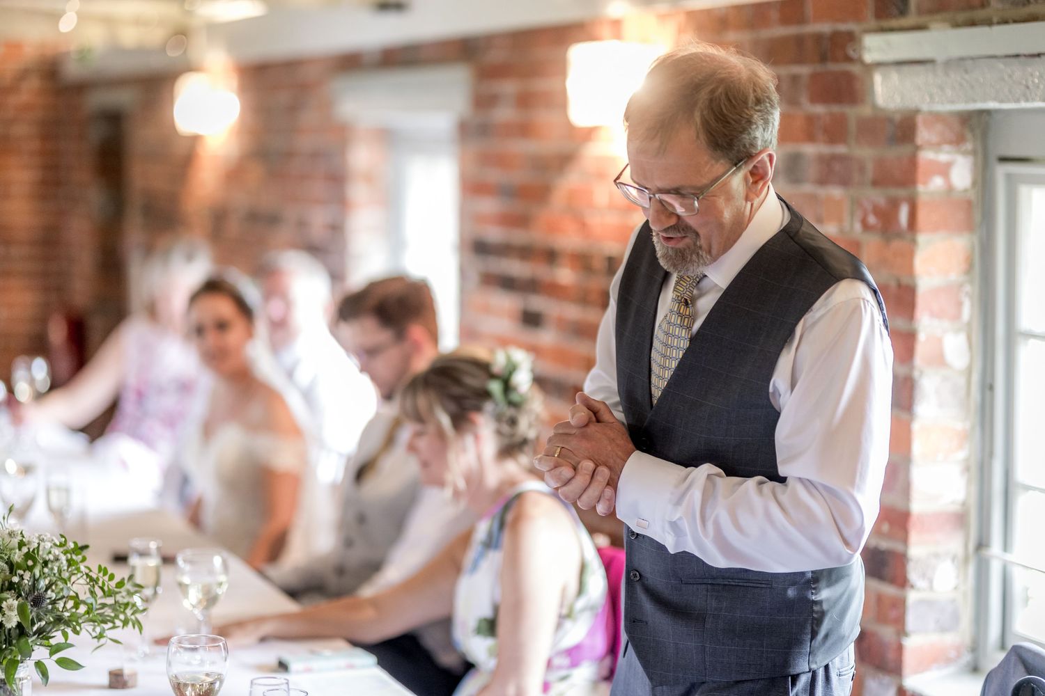 Wedding reception venue decorated with elegant table settings against rustic brick walls.