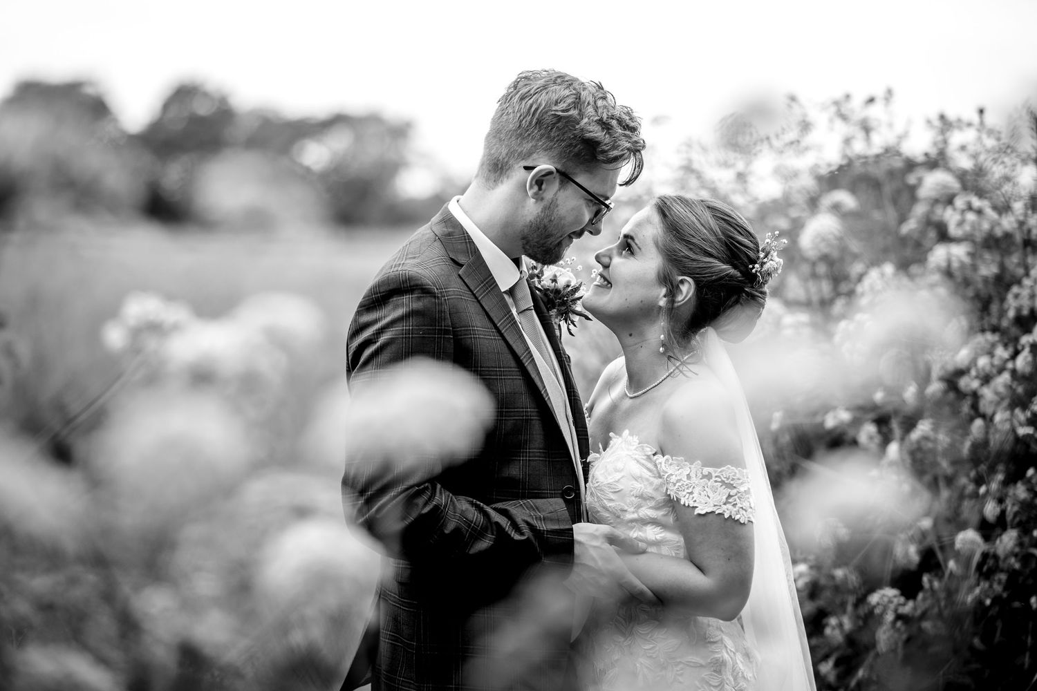 Intimate black and white wedding portrait with soft bokeh effect.