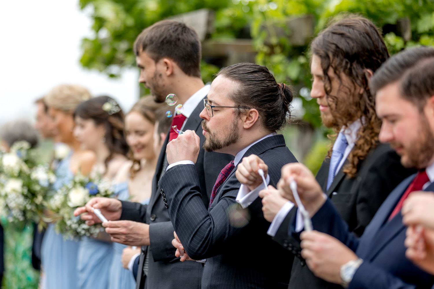 Wedding guests lined up outdoors sharing candid reactions during the celebration.