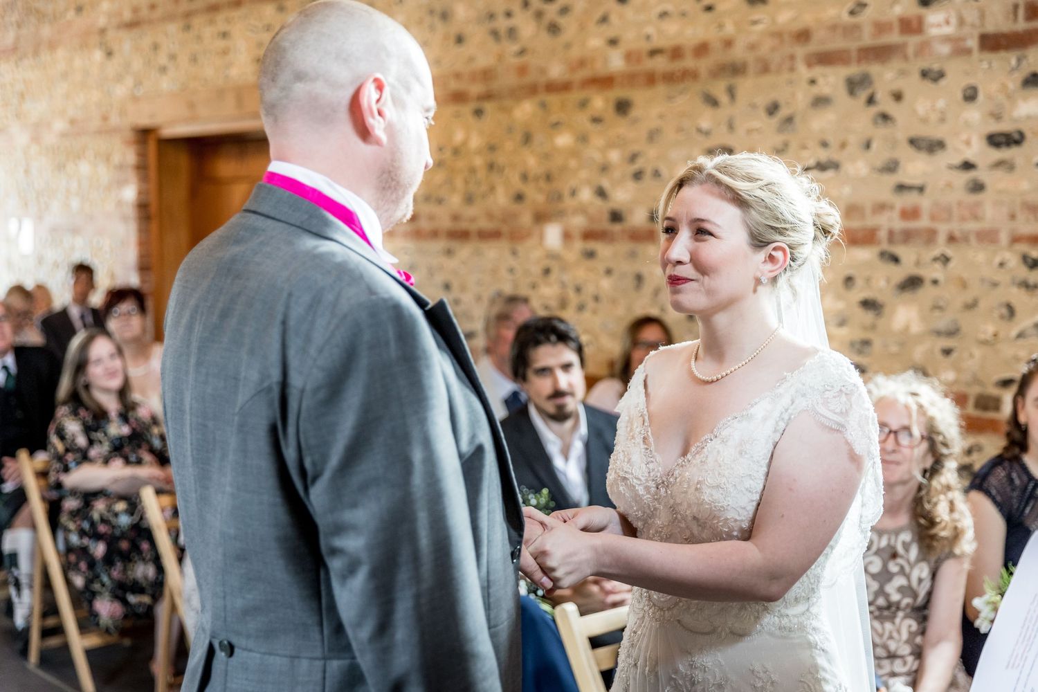 Wedding guests dance and celebrate during a reception in a rustic brick-walled venue.