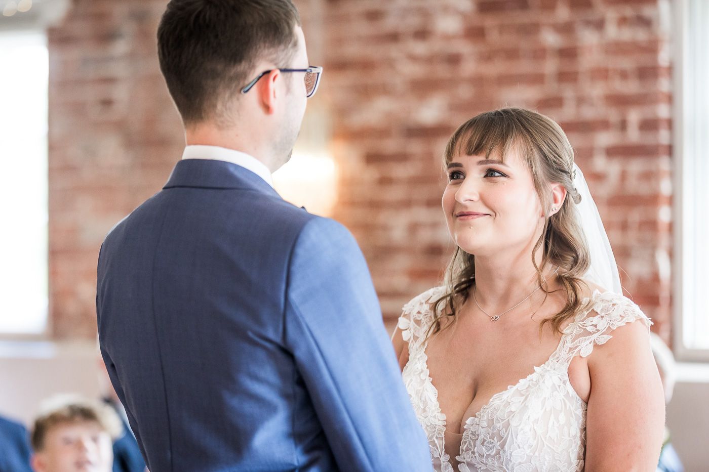 Indoor wedding ceremony moments in a venue with exposed brick walls and natural lighting.