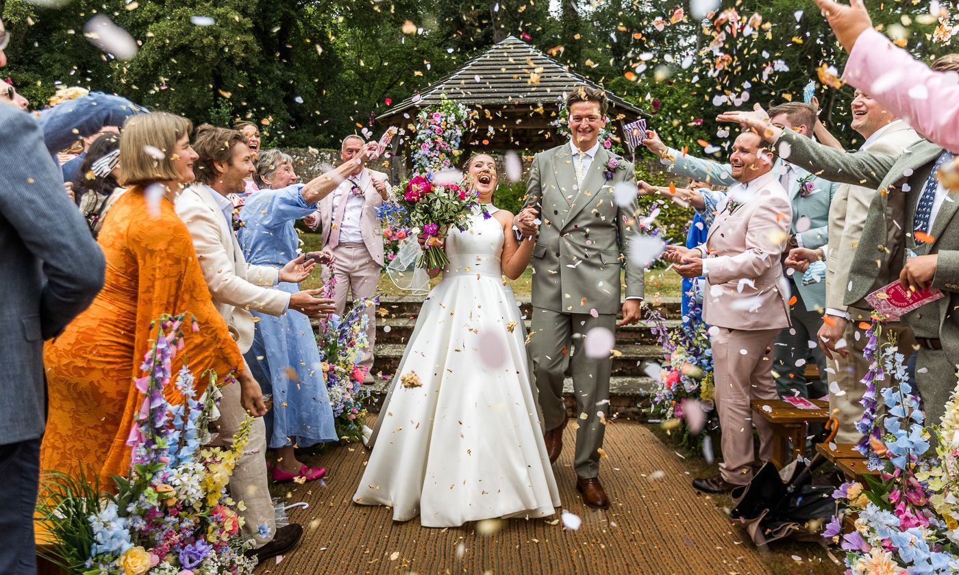 Wedding guests throwing colorful confetti during outdoor celebration.