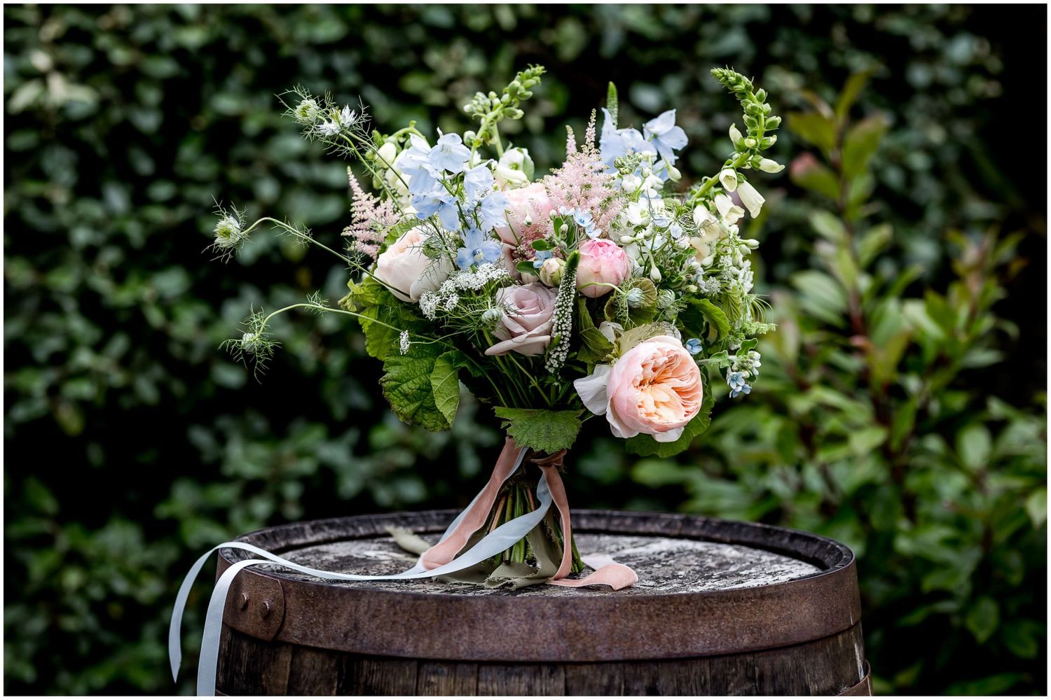 Garden-inspired floral arrangements featuring pink roses displayed on rustic wooden barrels.