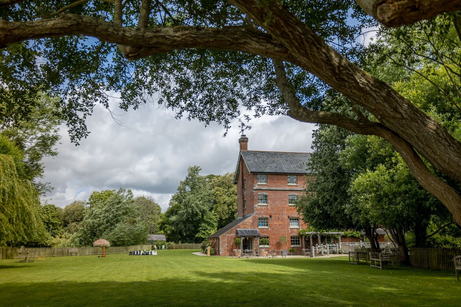 Panoramic view of historic brick buildings and grounds under sprawling oak trees.