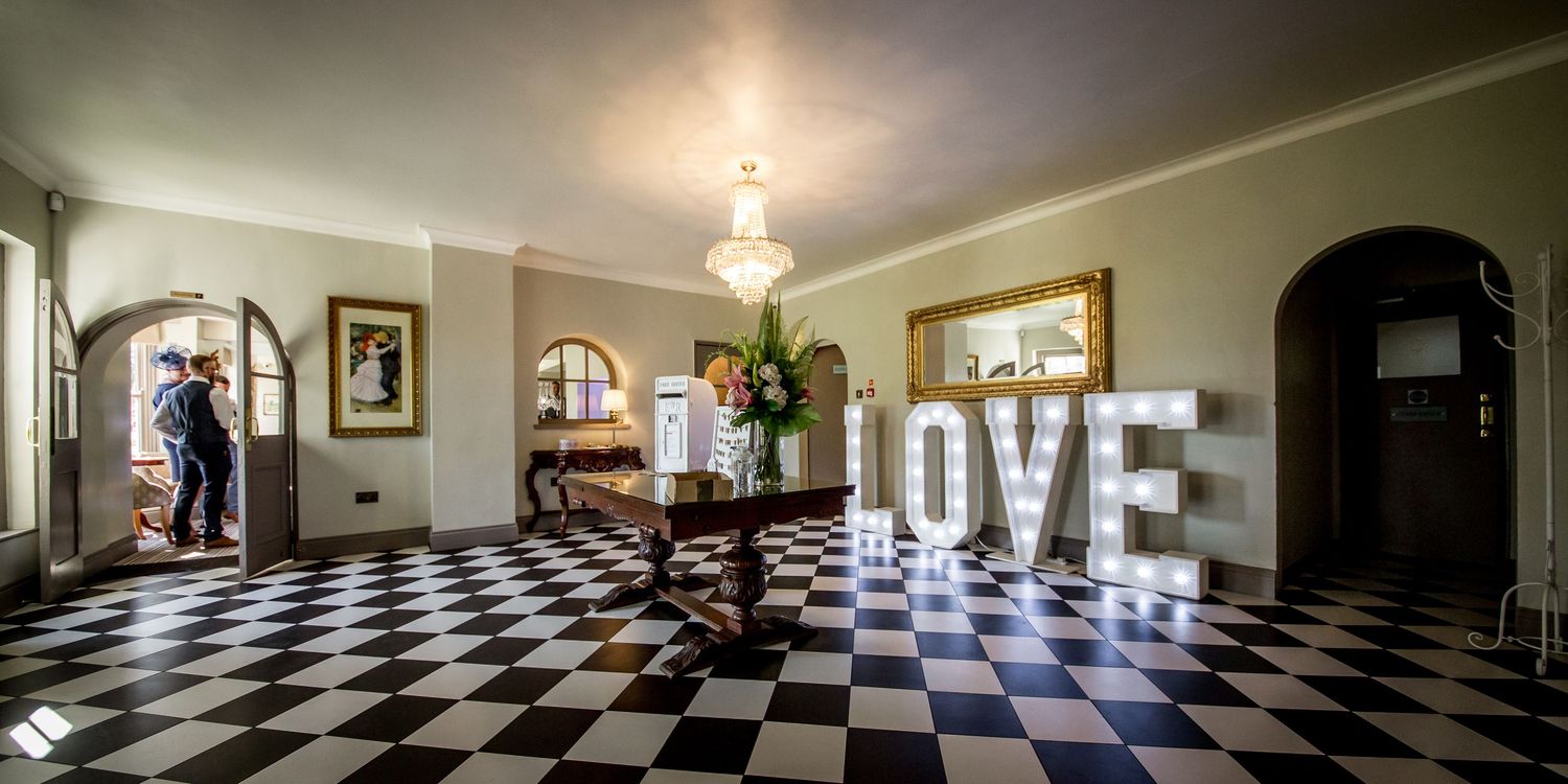 Interior panorama of wedding venue with checkered floor and elegant lighting.