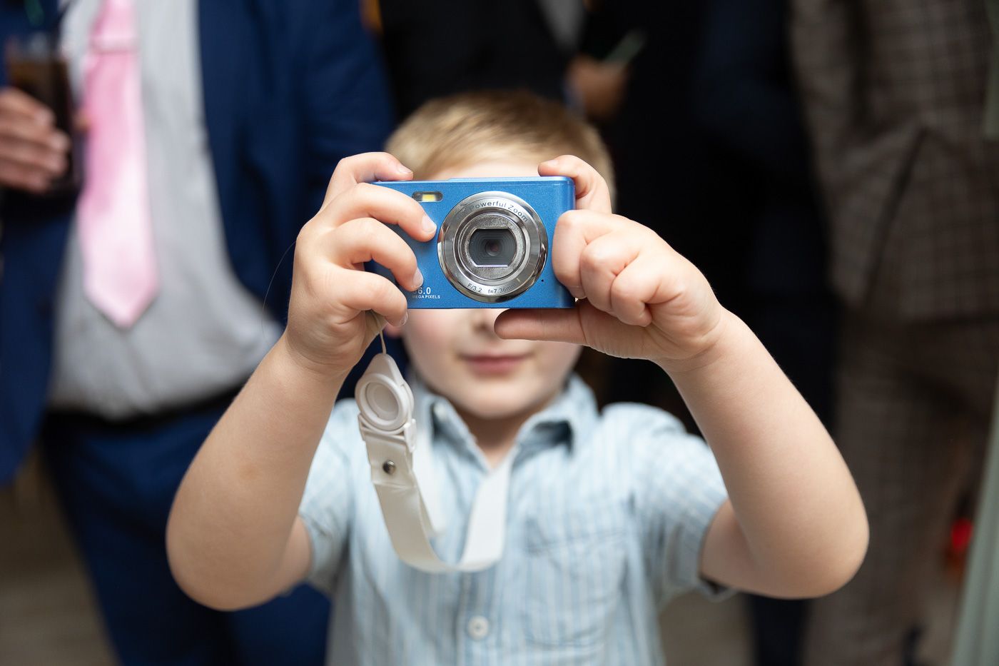 Young wedding guest taking photos with a digital camera during the celebration.