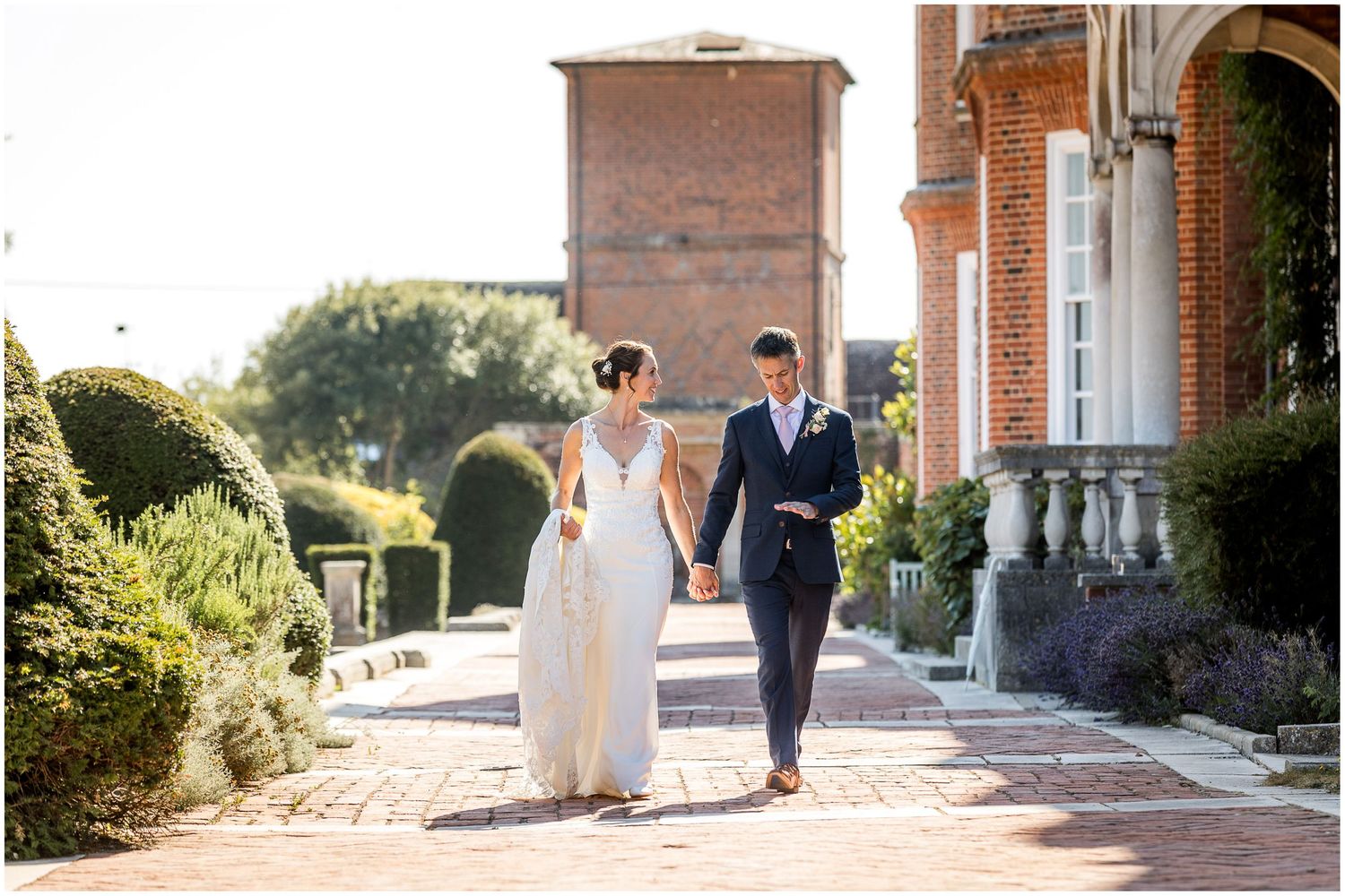 Bride and groom walk together through the gardens to the rear of the school