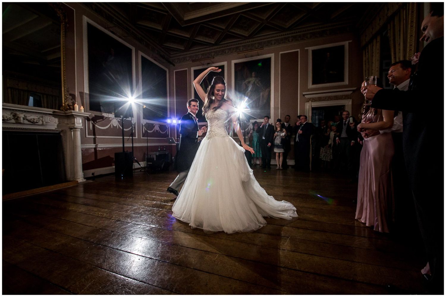 A couple dances together during their first dance at a wedding reception in a dimly lit ballroom.