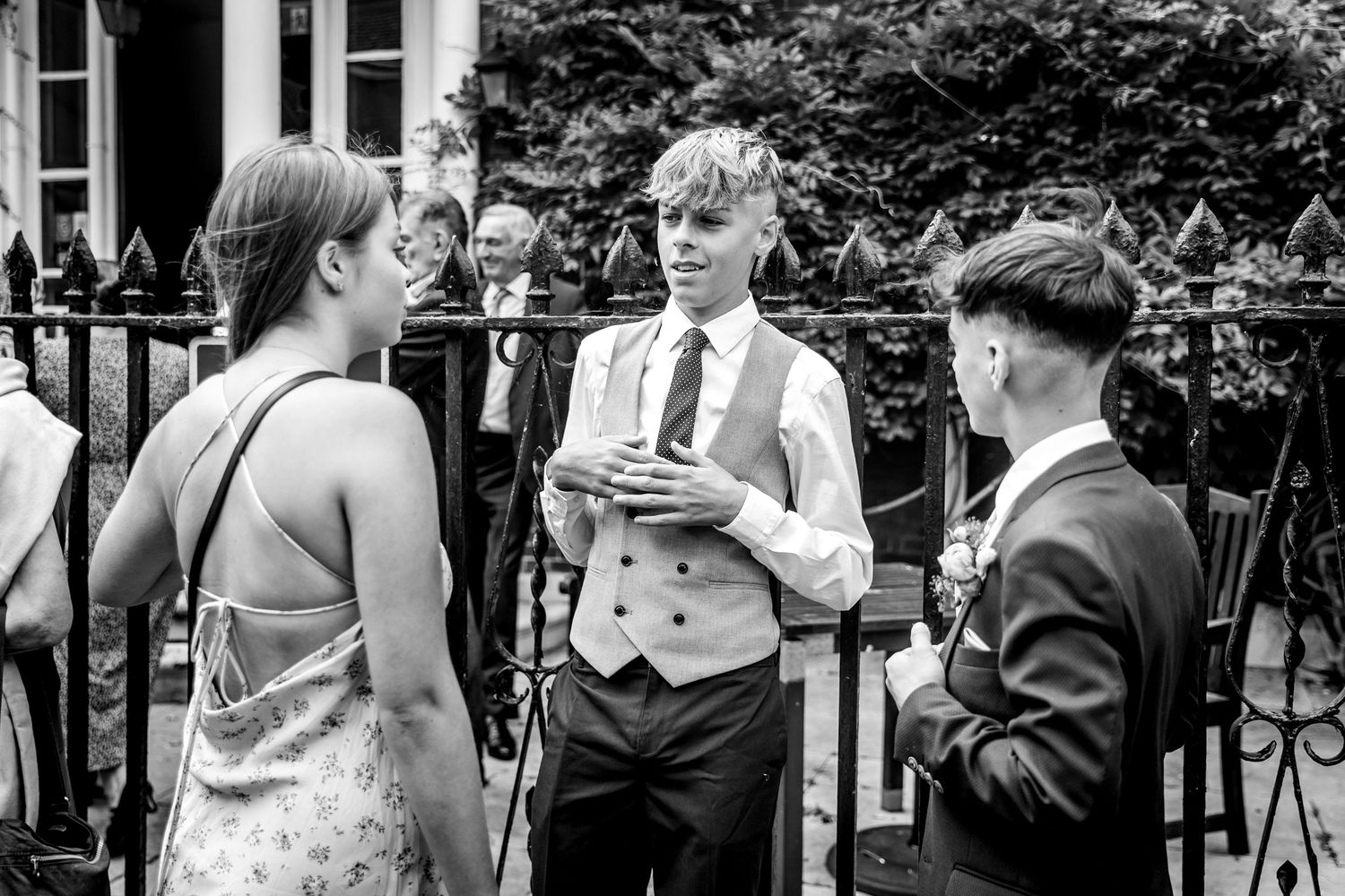 Black and white photo of wedding guests gathered outside a traditional building.