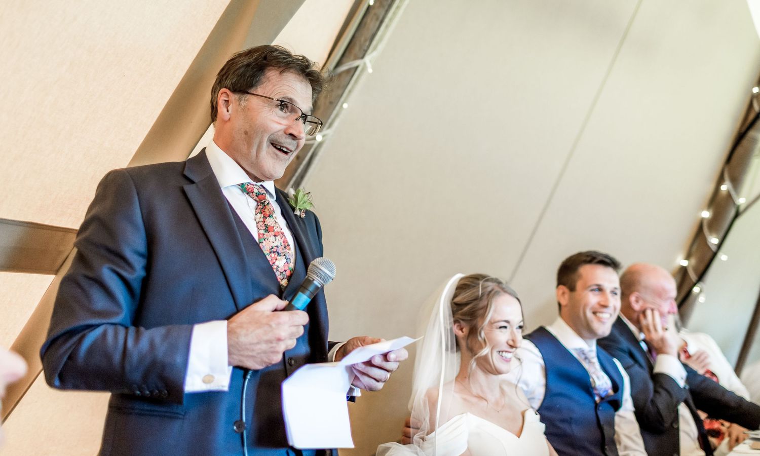 Wedding reception guests reacting emotionally to speeches in formal attire.