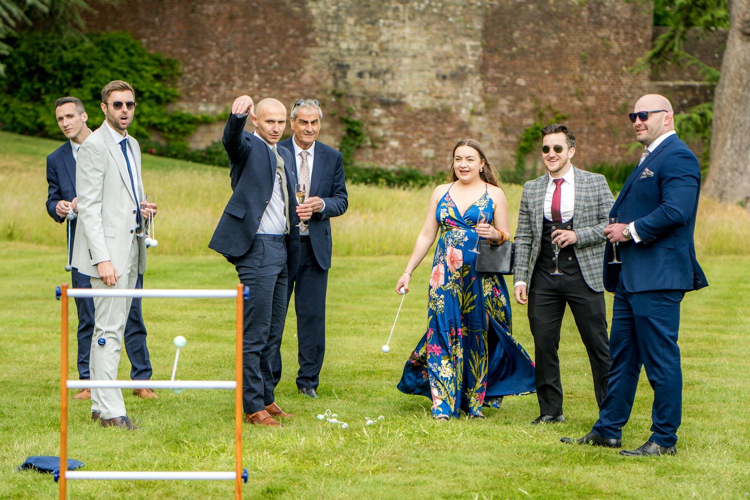 Group of wedding guests gathered around outdoor lawn games at a castle venue.