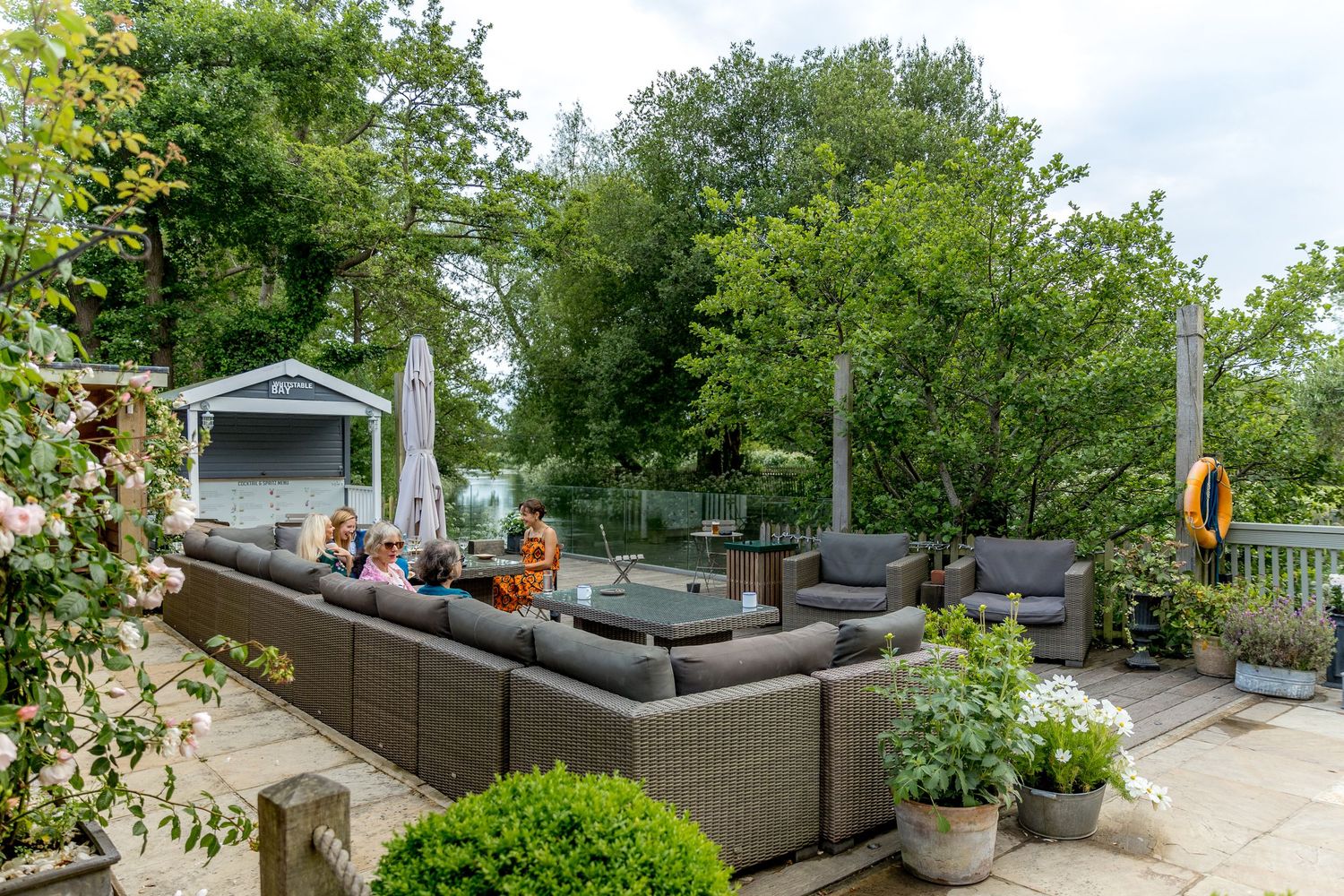 Outdoor garden seating area with wicker furniture and lush greenery.