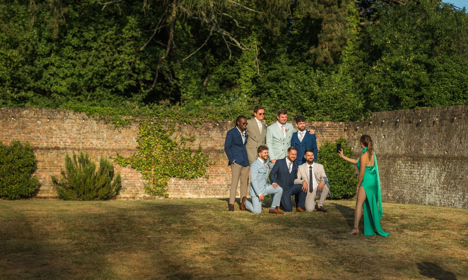 Wedding guests enjoy the last of the evening sun in the walled garden at Hampshire's Holywell Estate wedding venue