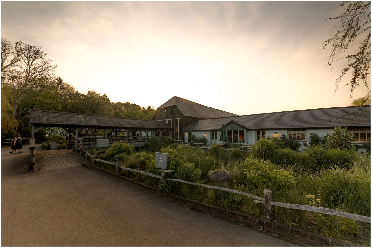 Panoramic view of a wedding venue with buildings and landscaping at sunset.