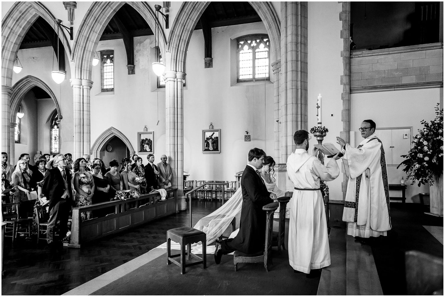 Black and white photograph of a religious ceremony in a Gothic church with arched columns.
