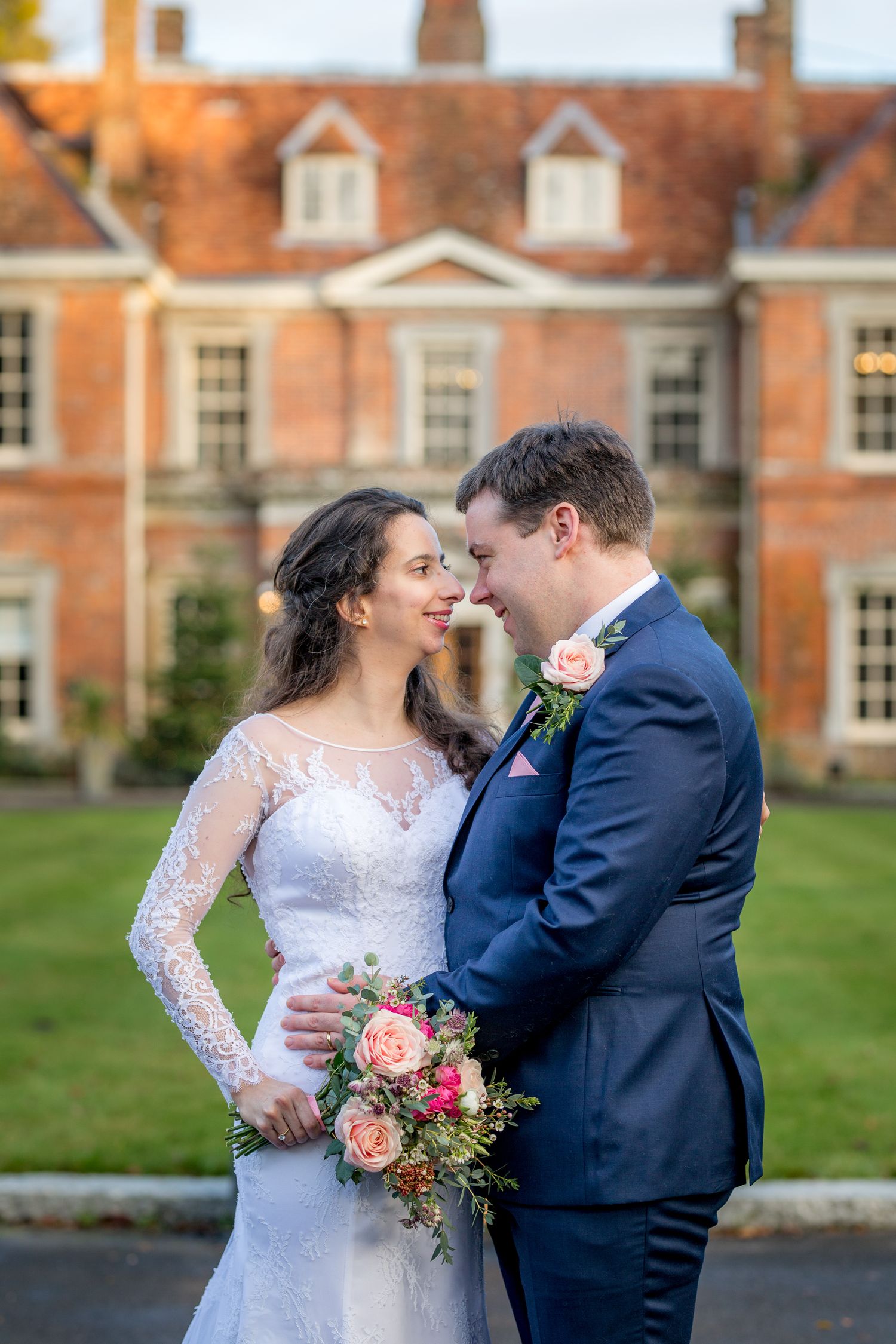 Elegant couple sharing a moment on the grounds of a historic brick estate.